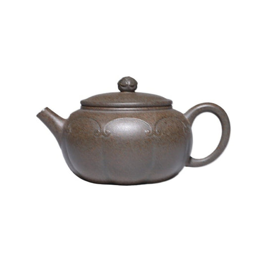 Grey-brown Dezhong teapot with raised scroll decoration, on a white background.