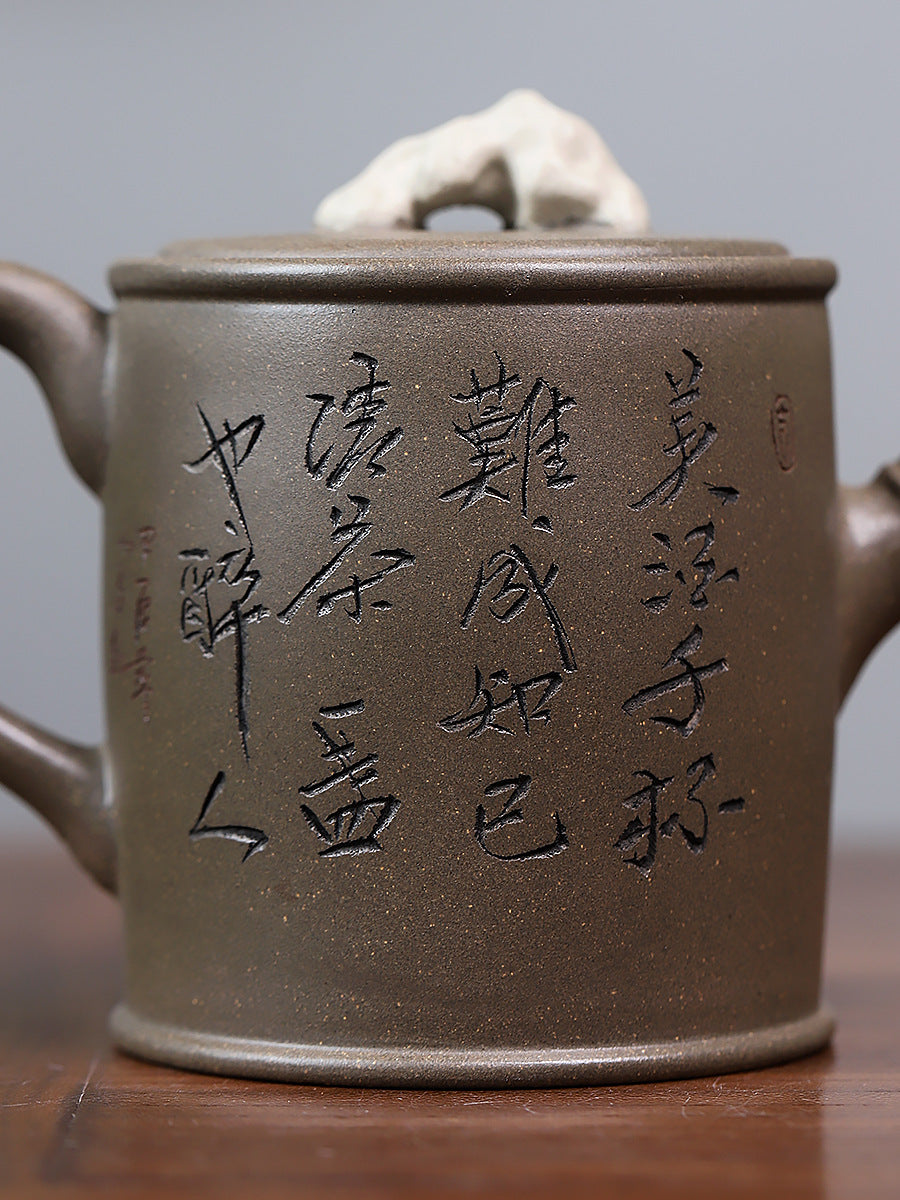 Grey-brown cylindrical teapot with bamboo decoration, close-up of calligraphy on the opposite side.