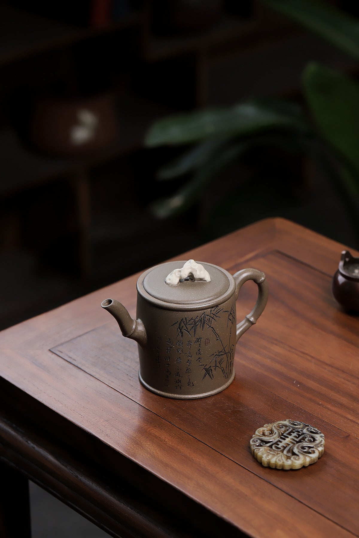 Grey-brown cylindrical teapot with bamboo decoration, viewed from above on a wooden table.