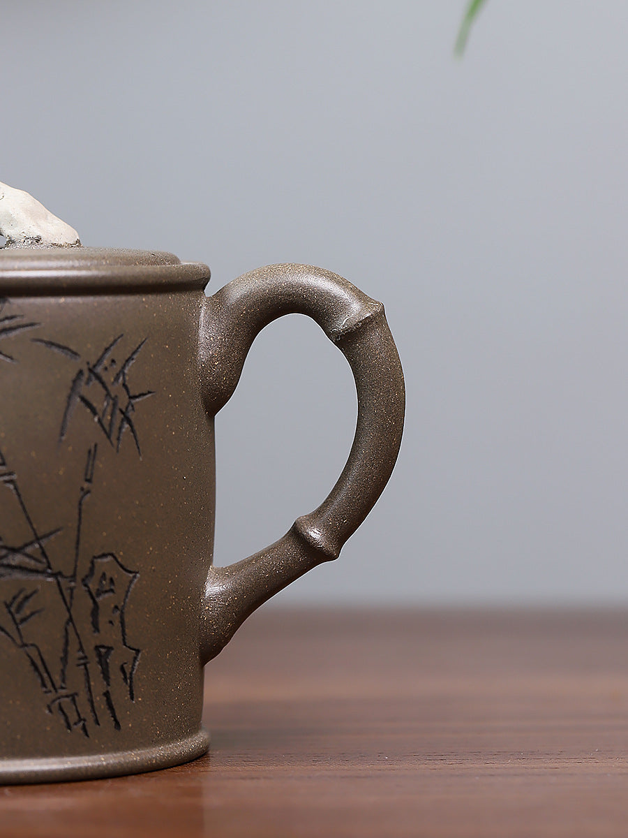 Grey-brown cylindrical teapot with bamboo decoration, bamboo-shaped loop handle close-up.