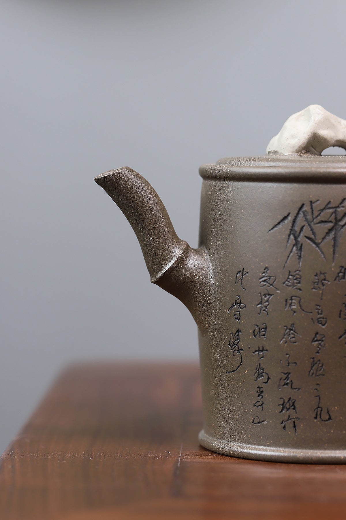 Grey-brown cylindrical teapot with bamboo decoration, bamboo-shaped spout close-up.