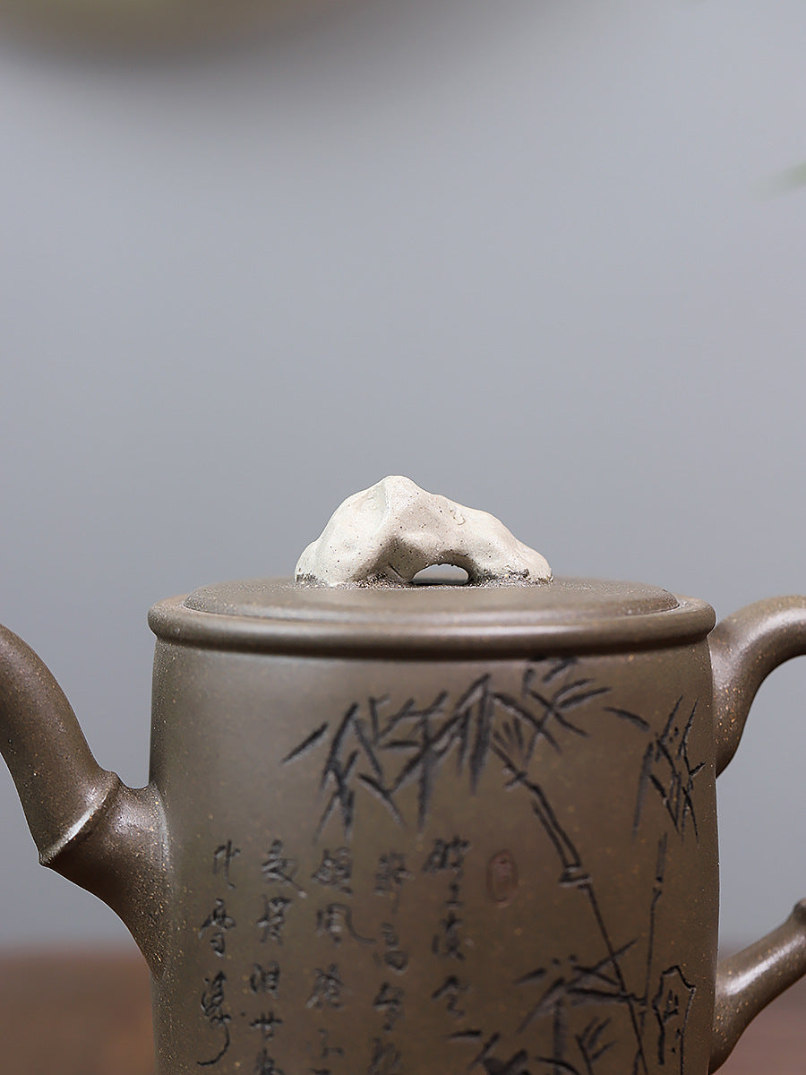 Grey-brown cylindrical teapot with bamboo decoration, close-up of the lid ornament and bamboo design.