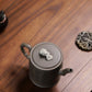 Grey-brown cylindrical teapot with bamboo decoration, overhead view of the lid ornament.