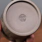 Grey-brown cylindrical teapot with bamboo decoration, base close-up showing an impressed seal.