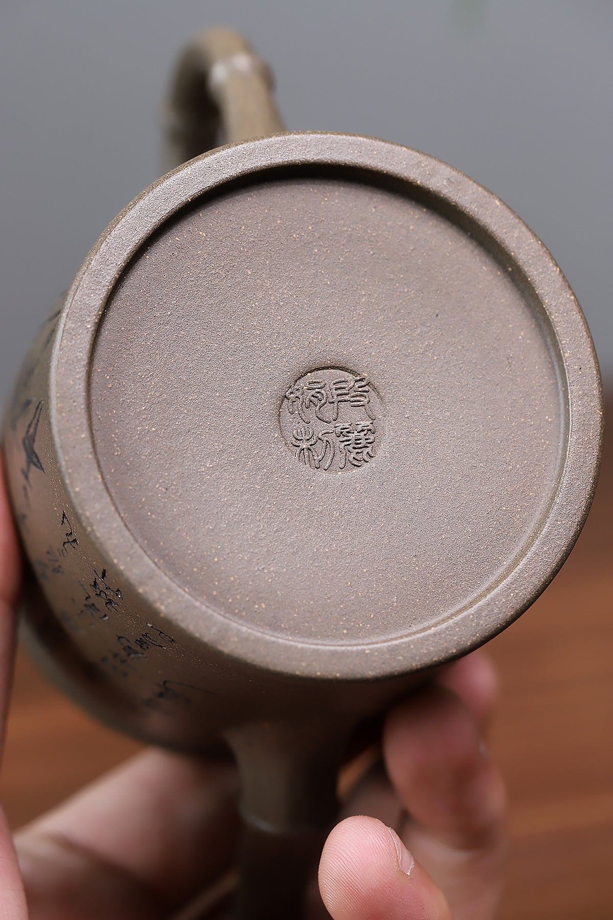 Grey-brown cylindrical teapot with bamboo decoration, base close-up showing an impressed seal.