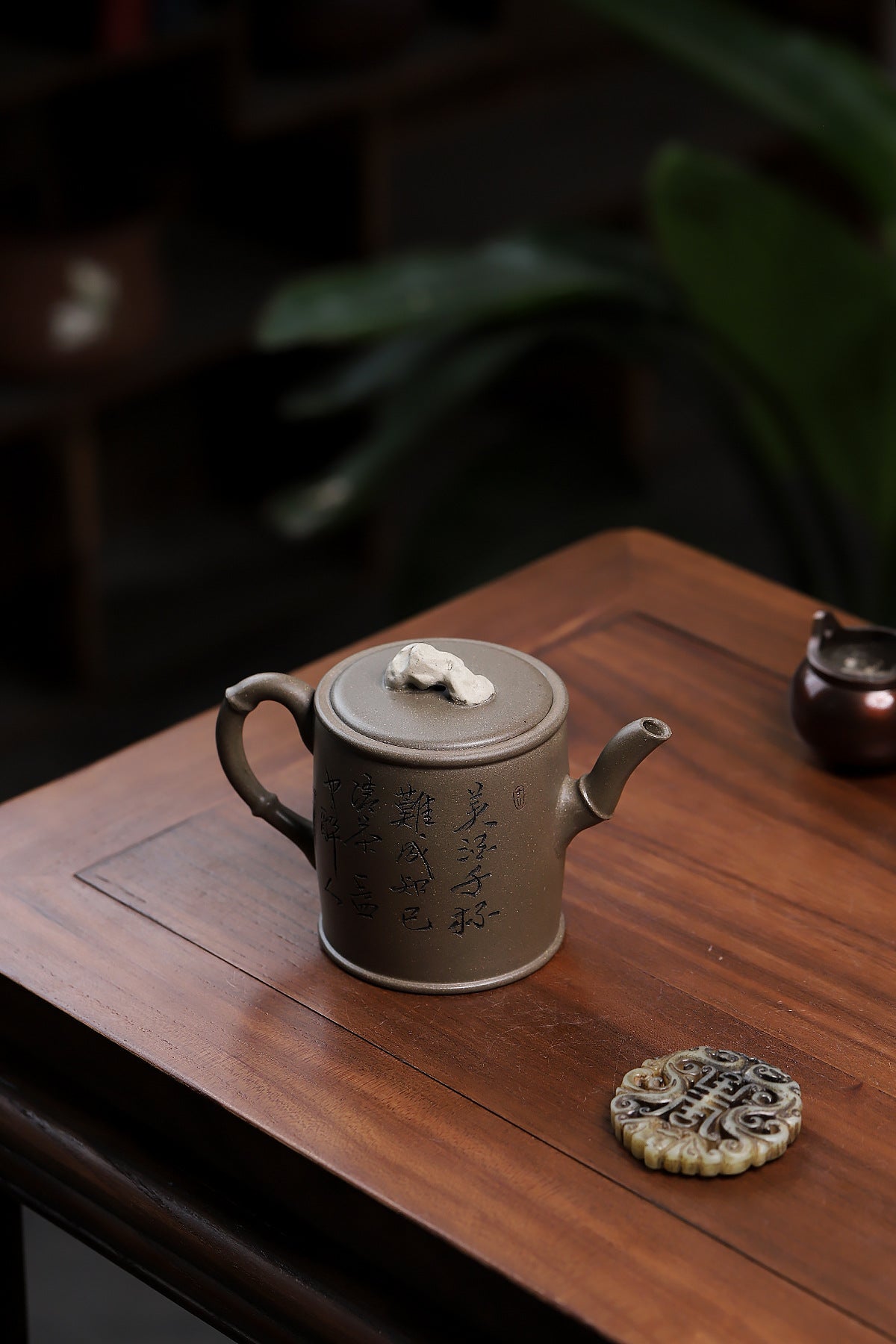 Grey-brown cylindrical teapot with bamboo decoration, opposite side viewed from above on a wooden table.