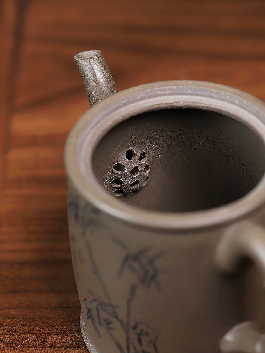 Grey-brown cylindrical teapot with bamboo decoration, interior close-up showing the perforated filter.