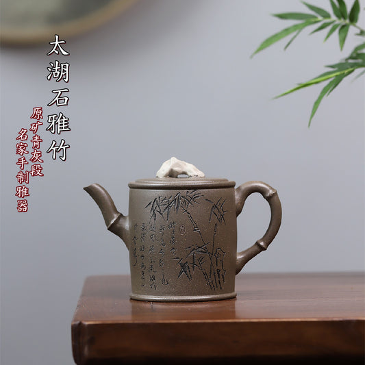Grey-brown cylindrical teapot with bamboo decoration, on a wooden table with Chinese text above.