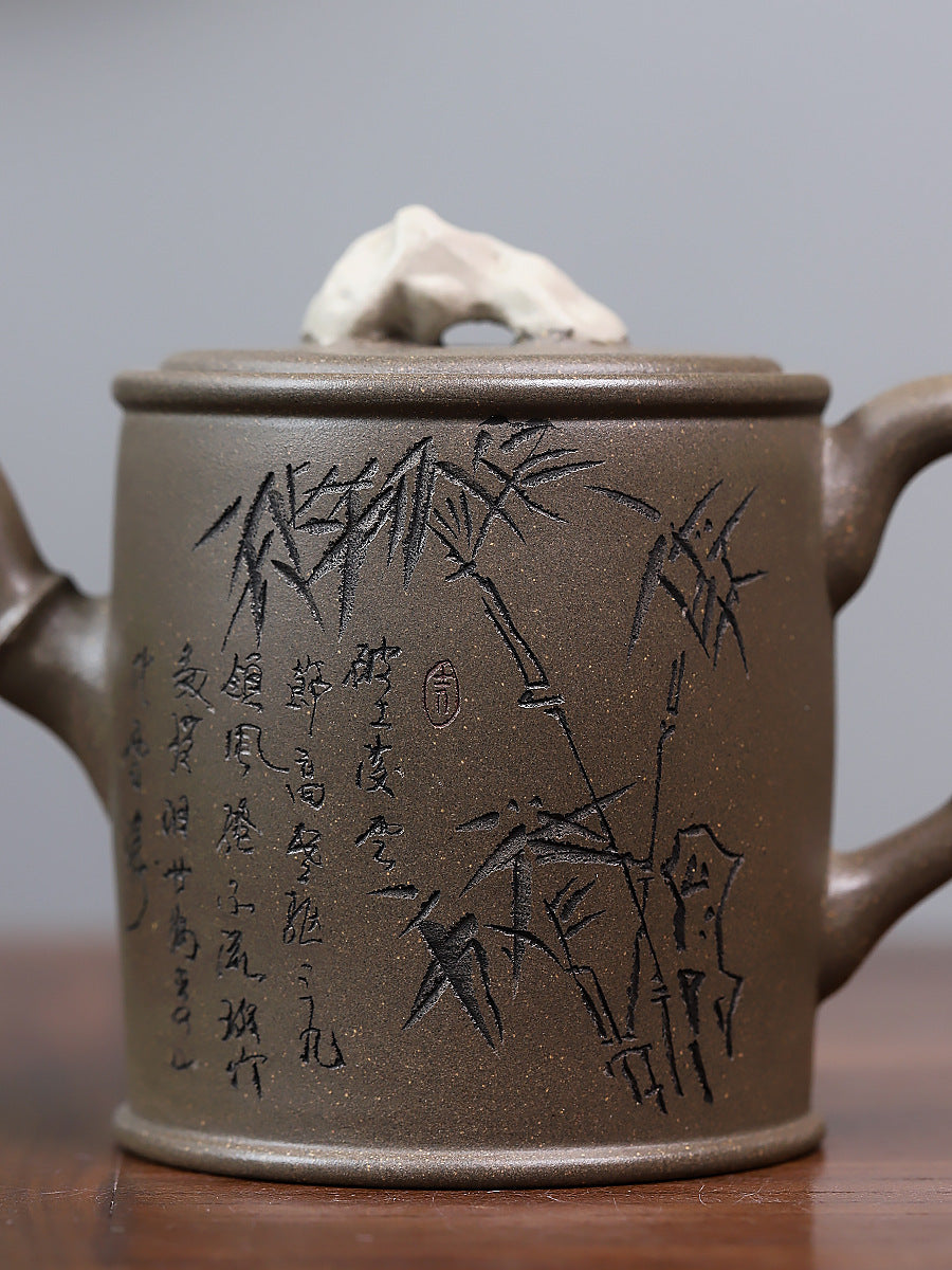 Grey-brown cylindrical teapot with bamboo decoration, close-up of bamboo and Chinese characters on the body.