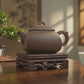 Yixing Zisha teapot in a peaceful tea setting with warm sunlight, a tea cup and green plant